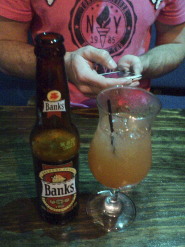 Can't decide? Have both. A cold Banks beer and a rum punch. But notice the phone - yes, I'm working. And yes, I AM wearing a pink shirt.